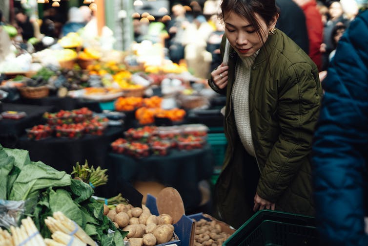 人們在農貿市場看蔬菜